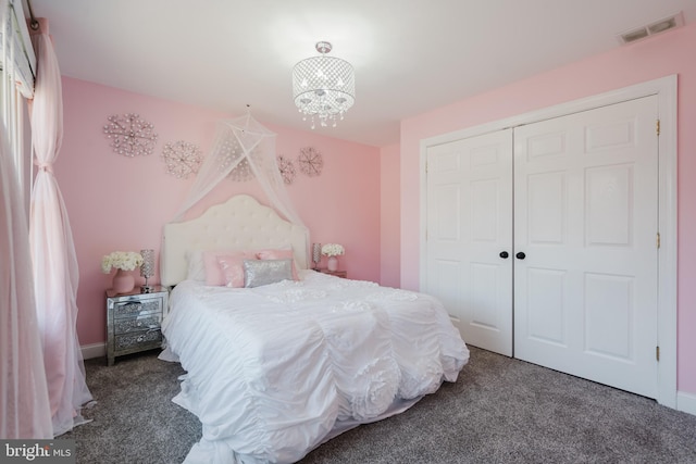 bedroom featuring dark colored carpet, an inviting chandelier, and a closet