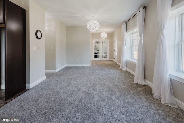 spare room featuring french doors, a chandelier, and carpet flooring