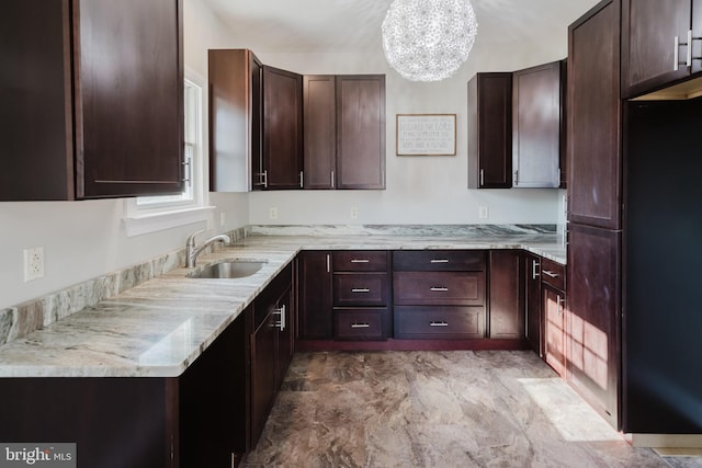 kitchen featuring sink, dark brown cabinets, and light stone countertops