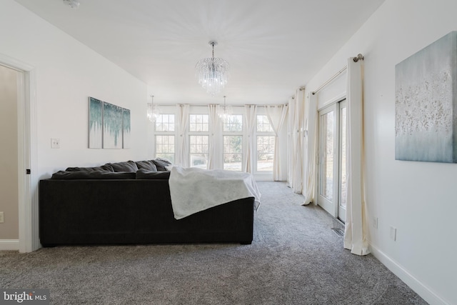 carpeted living room with an inviting chandelier