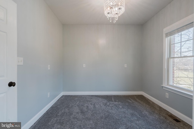 carpeted spare room with a chandelier