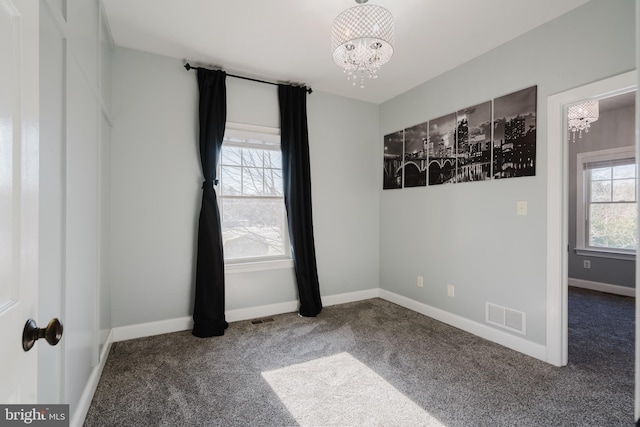 empty room with plenty of natural light, carpet, and a notable chandelier