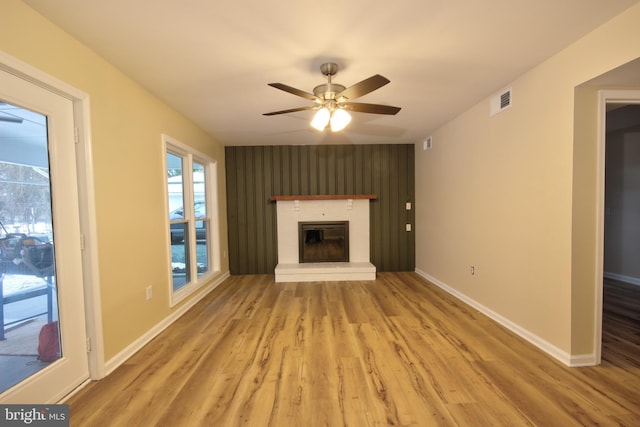 unfurnished living room featuring a brick fireplace, hardwood / wood-style flooring, and ceiling fan