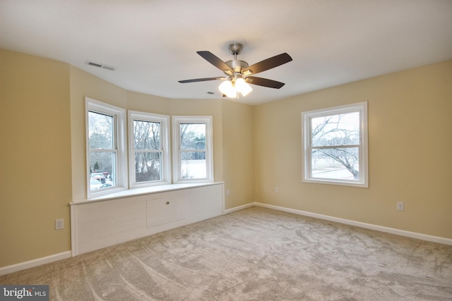 empty room featuring plenty of natural light, light colored carpet, and ceiling fan