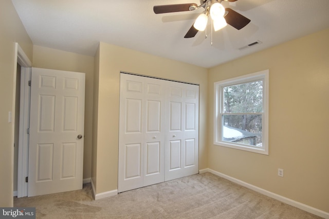 unfurnished bedroom featuring ceiling fan, light colored carpet, and a closet