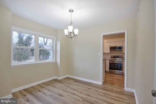 unfurnished dining area featuring an inviting chandelier and light hardwood / wood-style floors