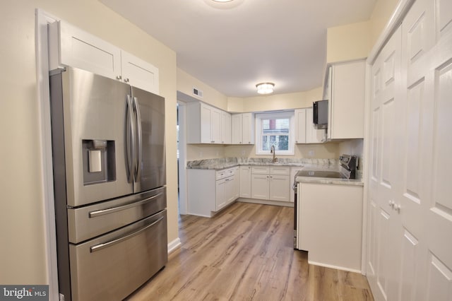 kitchen featuring white cabinetry, sink, stainless steel appliances, light stone countertops, and light wood-type flooring