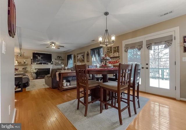 dining room featuring ceiling fan with notable chandelier, french doors, and light hardwood / wood-style floors