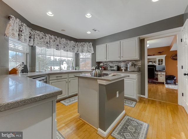 kitchen featuring black electric stovetop, a center island, light hardwood / wood-style floors, and decorative backsplash