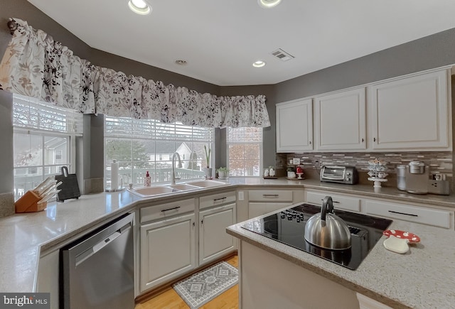 kitchen featuring black electric stovetop, dishwasher, sink, white cabinets, and plenty of natural light