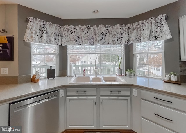 kitchen featuring white cabinets, a wealth of natural light, stainless steel dishwasher, and sink