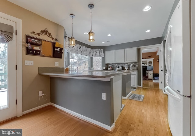 kitchen featuring white cabinetry, kitchen peninsula, white fridge, and light wood-type flooring