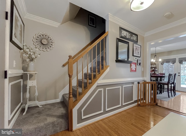 stairway featuring ornamental molding, hardwood / wood-style floors, and a notable chandelier