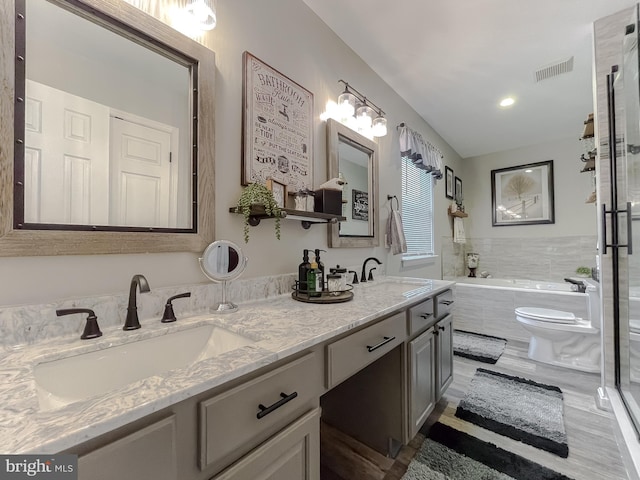 bathroom with tiled tub, toilet, and vanity