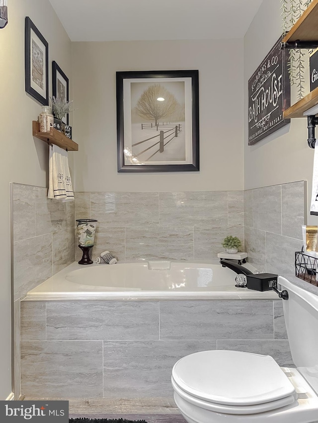 bathroom featuring toilet and a relaxing tiled tub