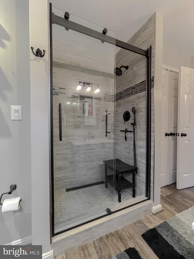 bathroom with hardwood / wood-style flooring and a shower with shower door