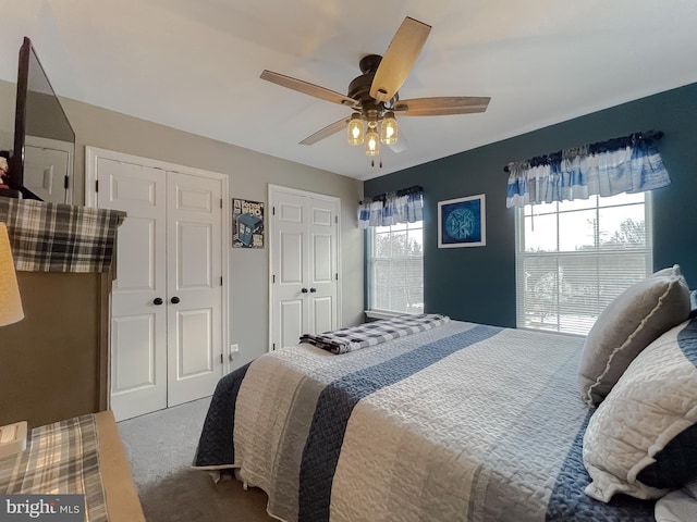 bedroom with ceiling fan, carpet, and two closets