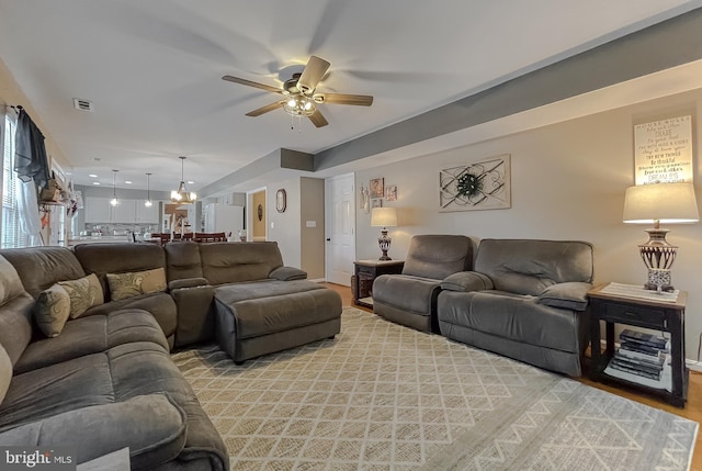 living room with ceiling fan with notable chandelier and light hardwood / wood-style flooring