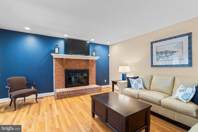 living room with a fireplace and light wood-type flooring