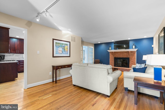 living room with track lighting, a fireplace, and light hardwood / wood-style floors