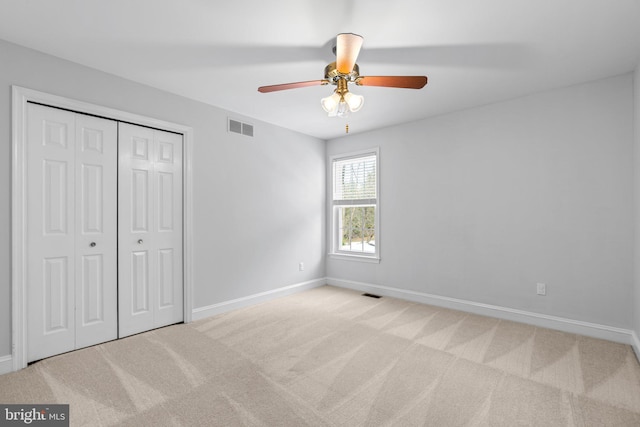 unfurnished bedroom featuring light carpet, ceiling fan, and a closet