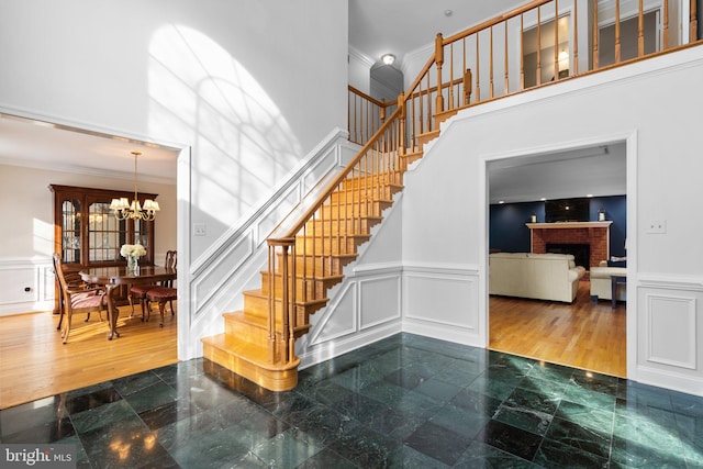 stairway featuring an inviting chandelier, a brick fireplace, and a high ceiling