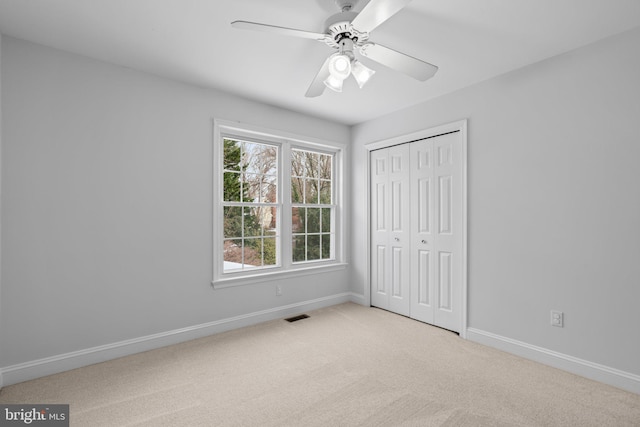 unfurnished bedroom featuring ceiling fan, light carpet, and a closet