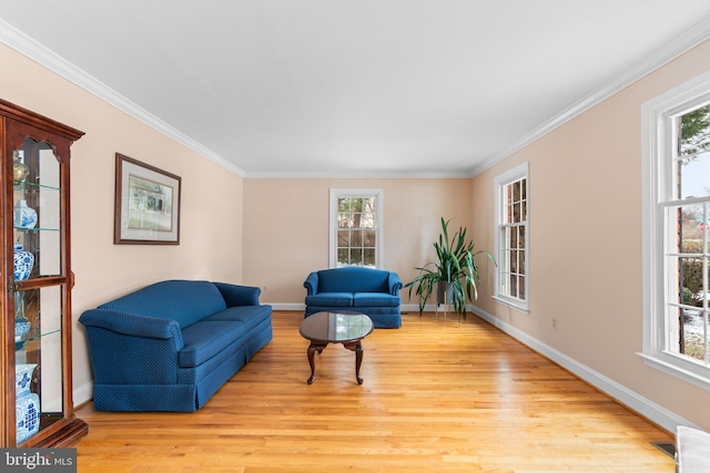 living area featuring ornamental molding, a healthy amount of sunlight, and light hardwood / wood-style flooring