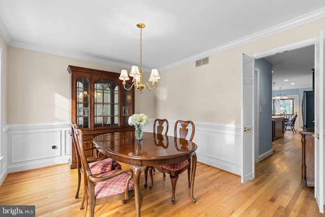 dining area featuring a notable chandelier, ornamental molding, and light wood-type flooring