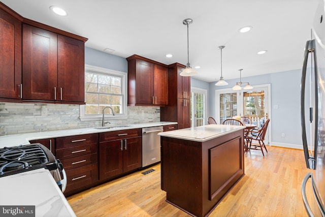 kitchen featuring sink, a center island, appliances with stainless steel finishes, pendant lighting, and backsplash