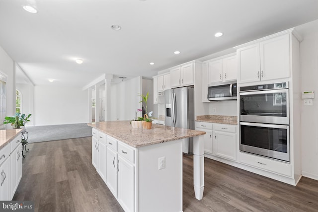 kitchen with a kitchen island, white cabinets, light stone countertops, and stainless steel appliances