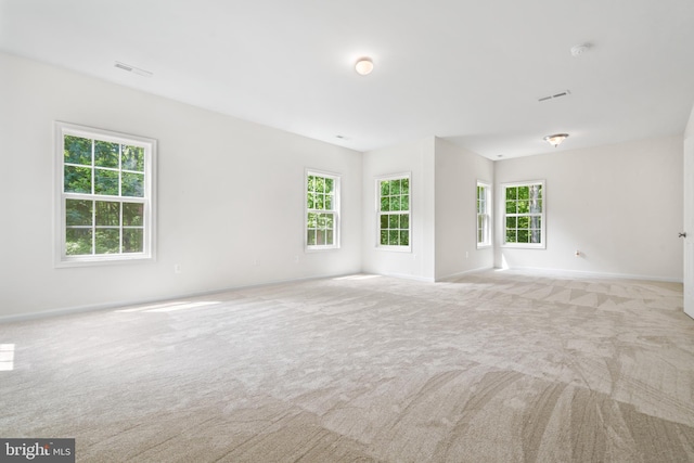 unfurnished room with light colored carpet and a wealth of natural light