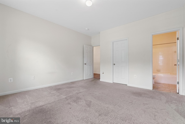 unfurnished bedroom featuring carpet floors and ensuite bath