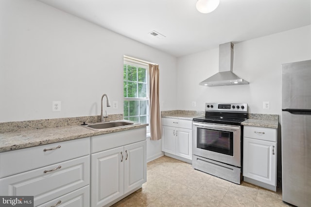 kitchen with appliances with stainless steel finishes, wall chimney range hood, white cabinets, sink, and light stone counters