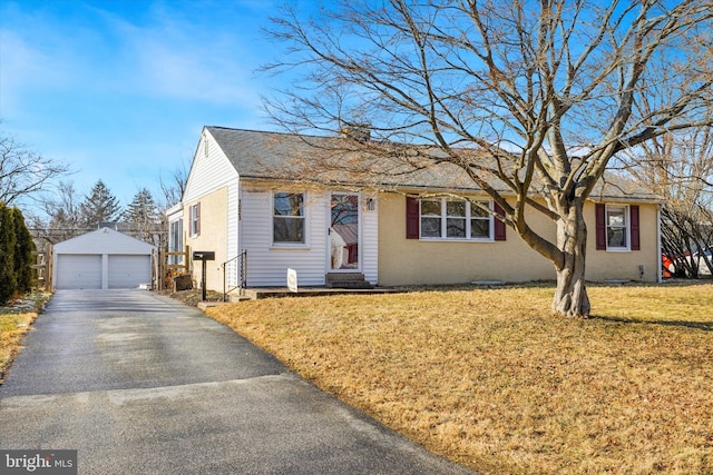 view of front of house featuring a garage, a front yard, and an outbuilding