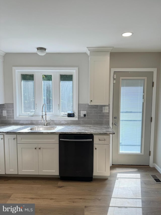 kitchen featuring white cabinetry, black dishwasher, tasteful backsplash, light stone countertops, and sink