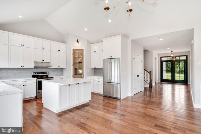 kitchen featuring backsplash, a kitchen island, white cabinetry, light stone countertops, and appliances with stainless steel finishes