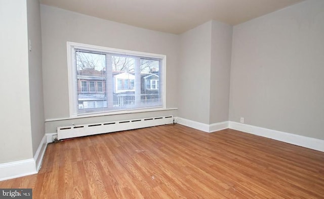 unfurnished room featuring light hardwood / wood-style floors and a baseboard radiator