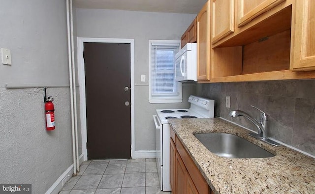 kitchen featuring light stone countertops, white appliances, decorative backsplash, sink, and light tile patterned floors