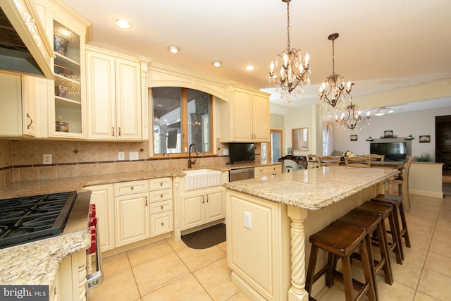 kitchen with cream cabinetry, a breakfast bar area, hanging light fixtures, a kitchen island, and sink