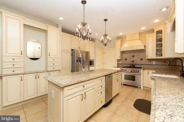 kitchen with premium range hood, appliances with stainless steel finishes, decorative backsplash, decorative light fixtures, and light stone counters