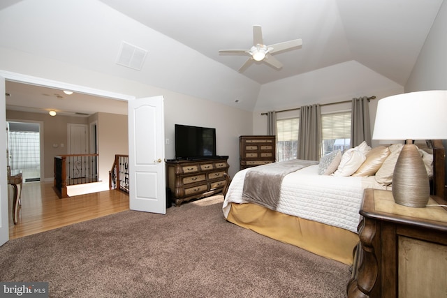 bedroom with ceiling fan, lofted ceiling, a raised ceiling, and dark colored carpet