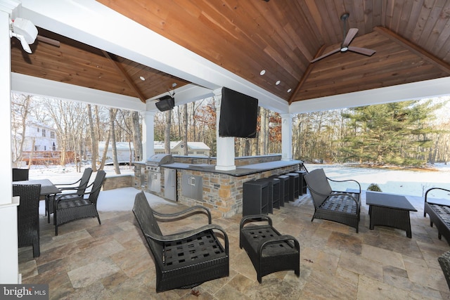 snow covered patio featuring grilling area, a bar, ceiling fan, a gazebo, and area for grilling