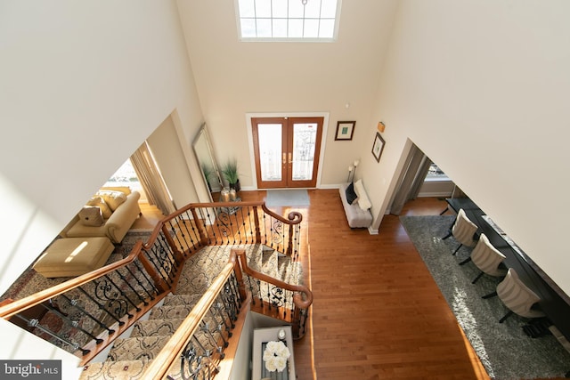 entrance foyer featuring dark wood-type flooring, french doors, a wealth of natural light, and a towering ceiling