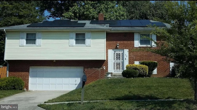 bi-level home with a garage, a front yard, and solar panels