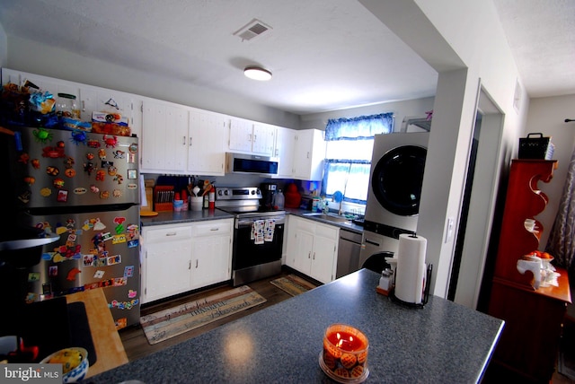 kitchen with white cabinets, stacked washer / drying machine, and appliances with stainless steel finishes