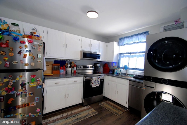 kitchen featuring white cabinets, appliances with stainless steel finishes, dark hardwood / wood-style flooring, stacked washer and dryer, and sink