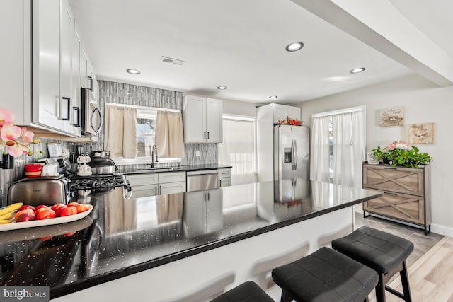 kitchen with white cabinetry, stainless steel appliances, tasteful backsplash, sink, and kitchen peninsula