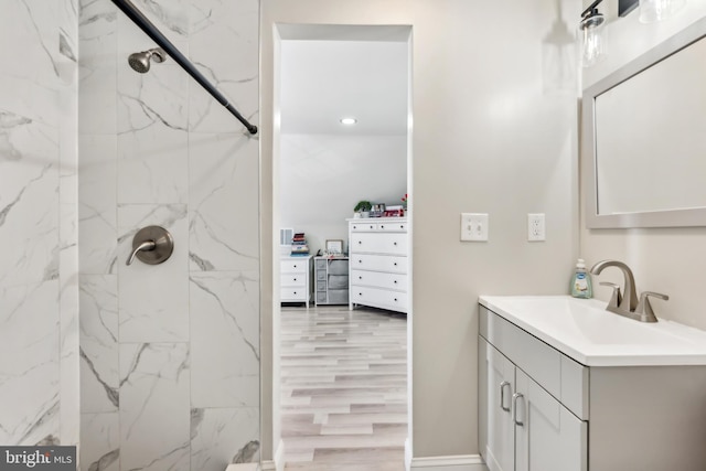 bathroom featuring hardwood / wood-style floors, vanity, and a tile shower