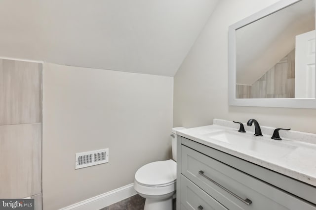 bathroom featuring vaulted ceiling, toilet, and vanity